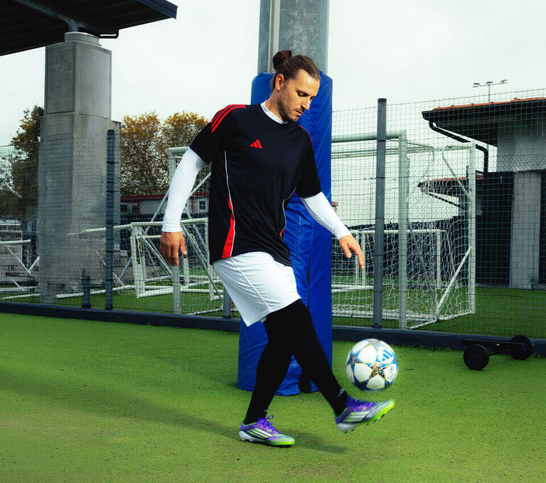 Ragazzo che si allena prima di una partita di calcio vestito con abbigliamento da allenamento football adidas
